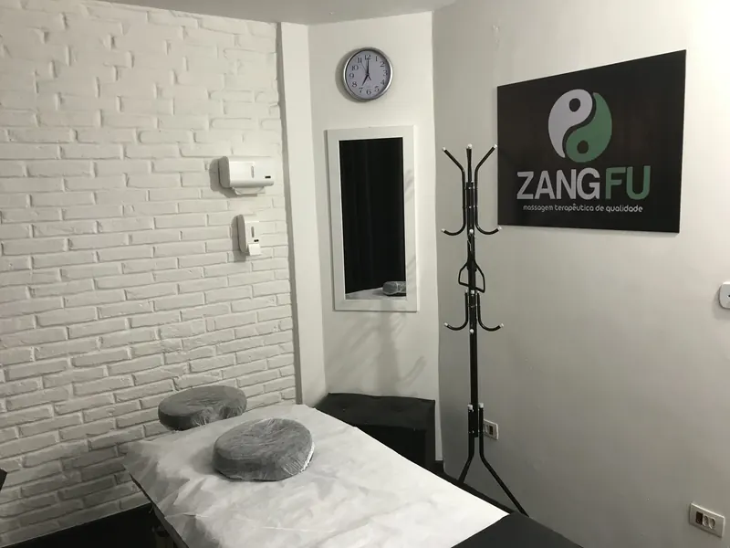 Sala de massagem da Zang Fu Consolação com maca preparada e parede de tijolinho branco