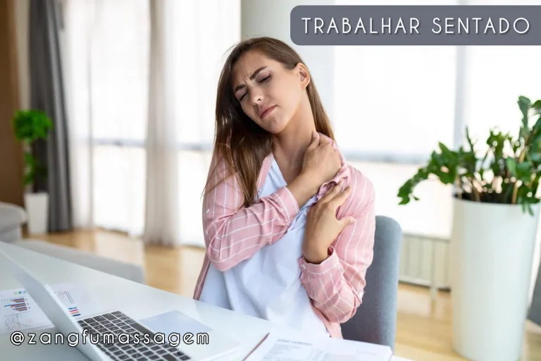 Mulher sentada em frente ao notebook massageando o pescoço e o ombro doloridos por trabalhar sentada